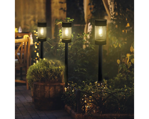 Tre solarlampor i trädgården på natten, vilket skapar en trevlig atmosfär.