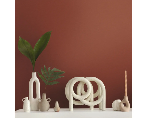 Dekorativa vaser och ljusstakar på en vit yta framför en färgad vägg