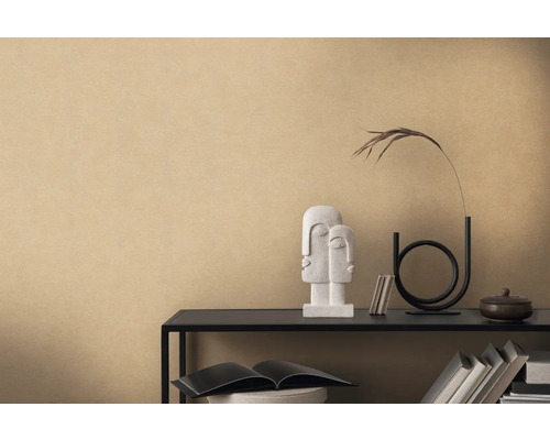 Dekorativt arrangemang med skulptur, vas och böcker på en hylla mot en beige vägg