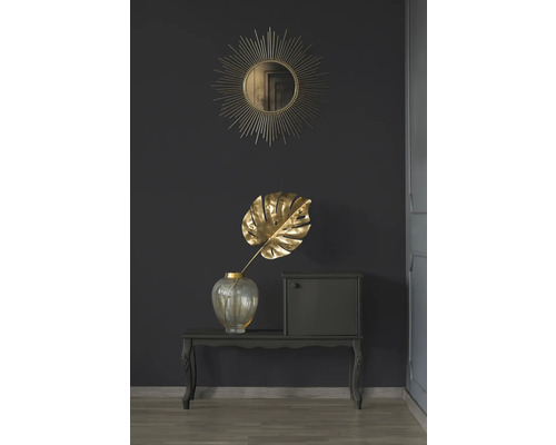 Dekorativ scen med spegel, Monstera blad i vas och litet skåp på ett bord