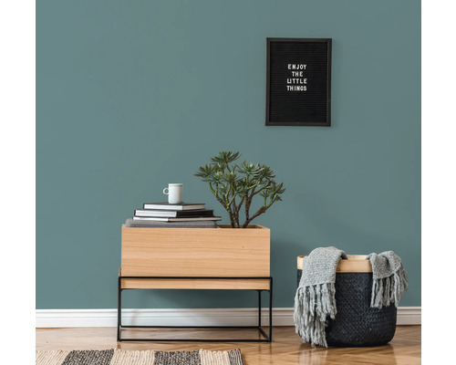 Dekorativt vardagsrum med byrå, växt, korg och väggmålning