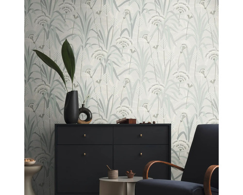Ett rum med en mönstrad tapet med en blommig design, en byrå och en fåtölj.