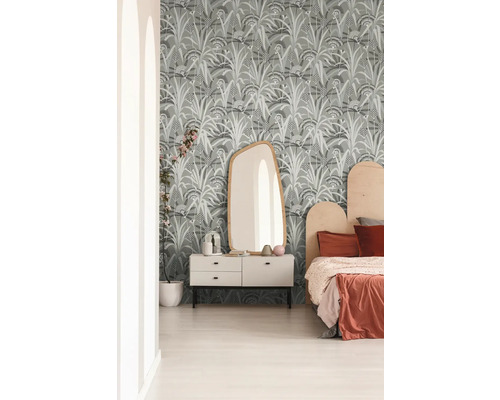 Sovrum med mönstrad tapet, byrå, spegel och säng