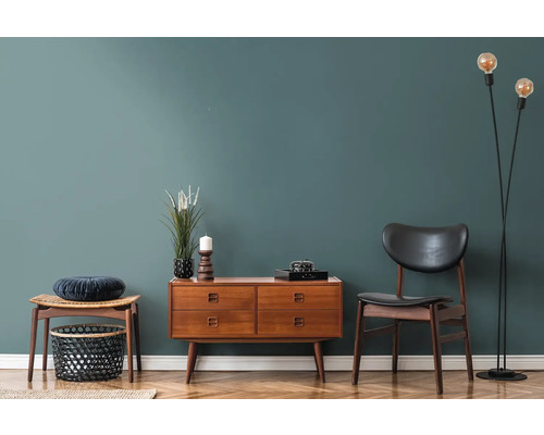 Vardagsrum med träbyrå, stol, pall och golvlampa på parkettgolv