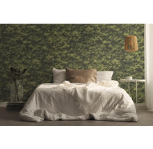 Sovrum med säng, sängbord, lampa och tapet med mossmotiv