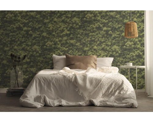 Sovrum med säng, sängbord, lampa och tapet med mossmotiv