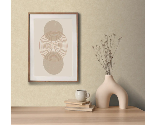 Dekorativ scen med ett inramat abstrakt konstverk, en vas med blommor, böcker och en kopp på ett bord.