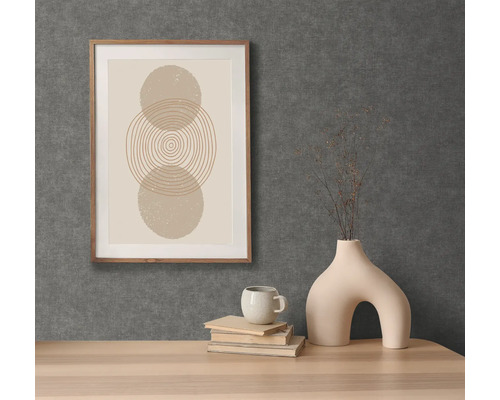 Dekorativ scen med ett inramat grafiskt tryck, en kopp, böcker och en ovanlig vas