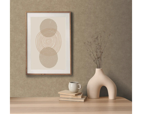 Dekorativ scen med inramad bild, vas, kopp och böcker på ett bord