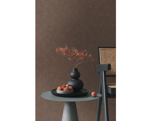 Dekorativ scen med vas, torkade blommor, litchis, sidobord och stol framför en vägg