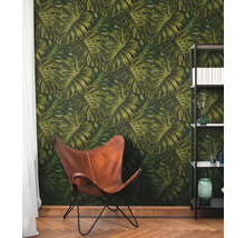 Rum med tapet med Monstera-bladmotiv, läderfåtölj och bokhylla