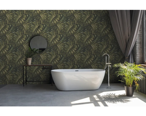 Badrum med fristående badkar, konsolbord med spegel och krukväxter framför en vägg med bladmönstrad tapet.