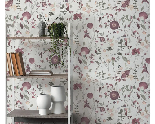 Hylla med dekorativa föremål framför en blommig tapet
