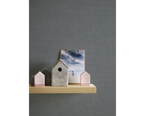 Dekorativ scen med grå tapet, trähylla, hus och ett fotografi