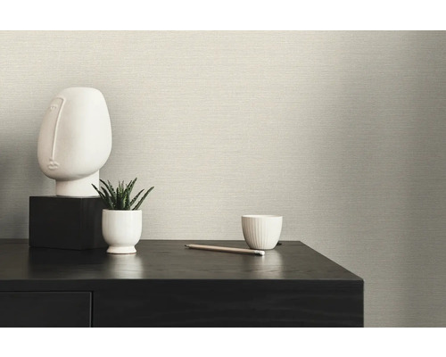 Scen med textilväggbeklädnad, bord, skulptur och växt