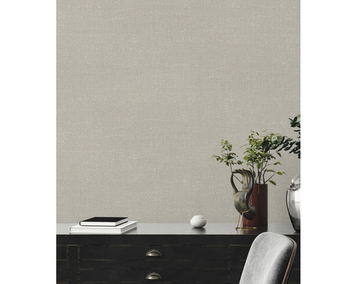 Närbild av en vägg med en beige textilväv ovanför en skänk.