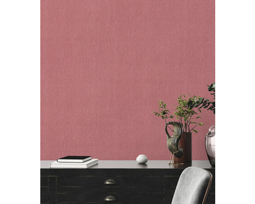 Närbild av en vägg med textil tapet i linneoptik, kombinerat med en byrå och dekorativa element.