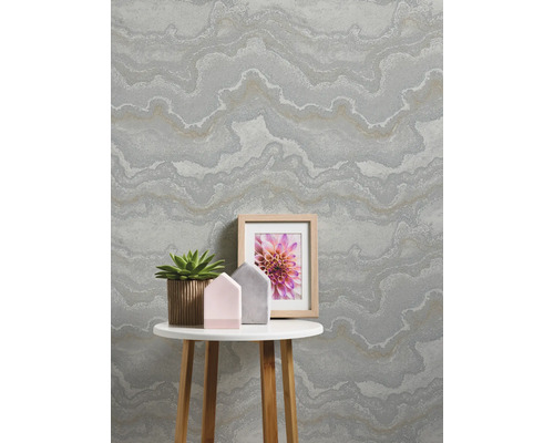 Vardagsrum med mönstrad tapet, bord, växt och fotoram