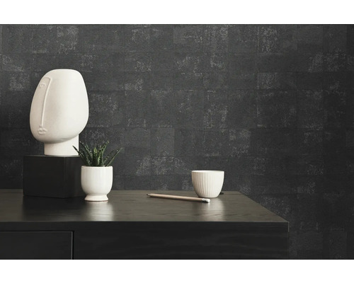 Närbild av ett rum med en svart byrå, en vit byst, en växt, en kopp och en penndekoration framför en mörk vägg