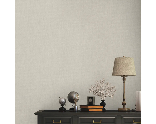 Vägg med beige tapet och byrå med dekorationer