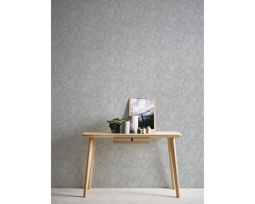 Miljöbild med ett träskrivbord mot en grå mönstrad tapet.