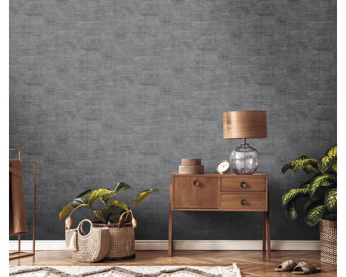 Vardagsrum med grå strukturtapet, träbyrå, bordslampa och krukväxter.
