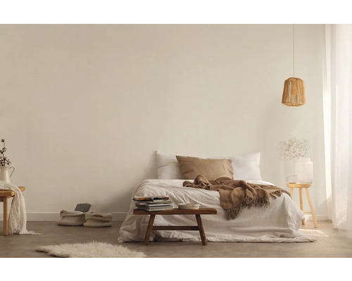 Ljust sovrum med säng, filt, kuddar, sidobord, lampa och dekorativa element för en vänlig atmosfär.