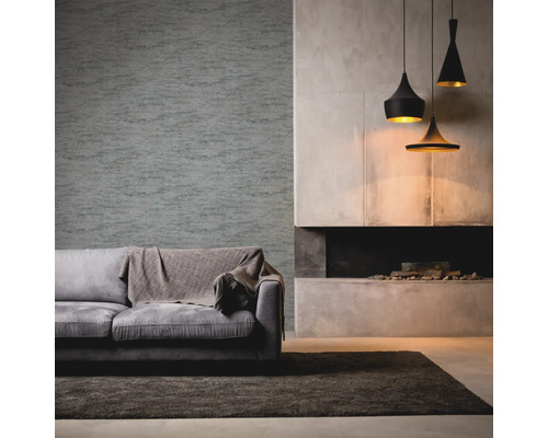 Vardagsrum med grå soffa, filt, mönstrad tapet, öppen spis och hänglampor