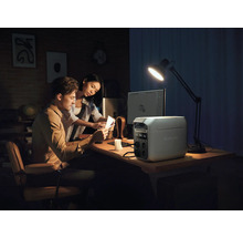 Ett par arbetar vid ett skrivbord med en EcoFlow-kraftstation, en dator och en skrivbordslampa.