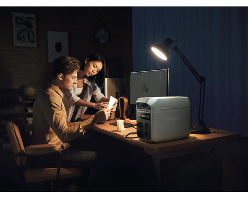 Ett par arbetar vid ett skrivbord med en EcoFlow-kraftstation, en dator och en skrivbordslampa.