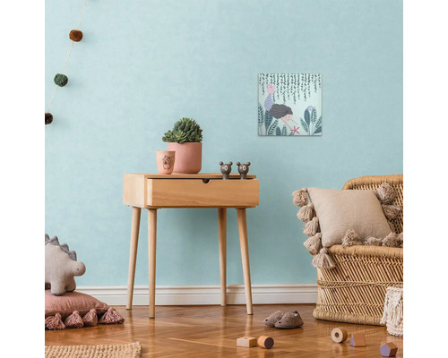 Dekorativ barnrumsscen med sidobord i trä, canvastryck, krukväxter och rottingfåtölj