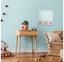 Barnrumsinredning med canvastavla, sidobord och rottingfåtölj.