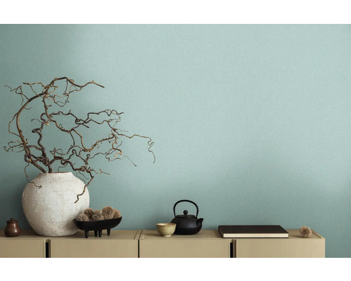 Dekorativ interiör med vas och grenar framför en vägg