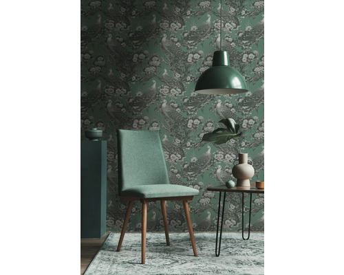 Inredningsexempel med en grön tapet med fågelmotiv, en grön stol och en matchande lampa