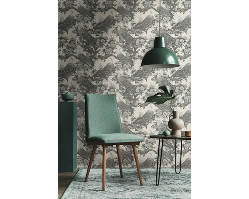 Vardagsrum med mönstrad tapet med påfåglar, stol, bord och hänglampa