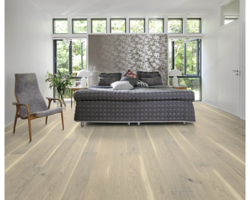 Ljust sovrum med trägolv, säng och fåtölj