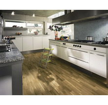 Ljust kök med vita skåp, bänkskiva i sten och trägolv.