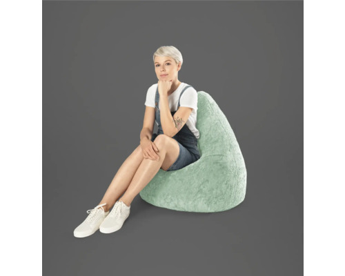 Kvinna sitter på en droppformad sittsäck av konstpäls