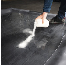 En person häller ett vitt pulver på en svart folie.