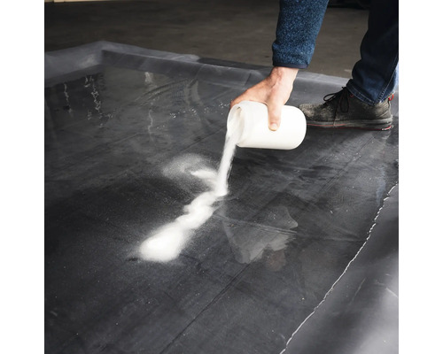 En person häller ett vitt pulver på en svart folie.