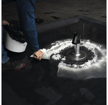 En person skottar en vit substans runt ett avlopp i en sopsäck.