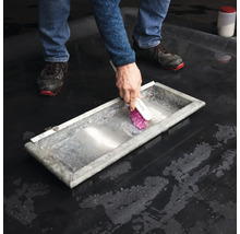 Person rengör ett metalltråg med en borste.