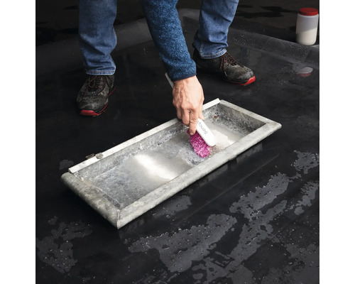 Person rengör ett metalltråg med en borste.