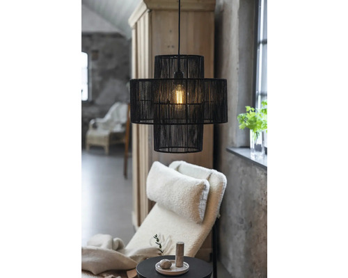 Svart hänglampa med tre nivåer ovanför en fåtölj och ett sidobord i ett vardagsrum.