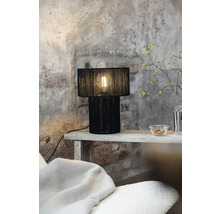 Dekorativ bordslampa med svart lampskärm på ett sidobord