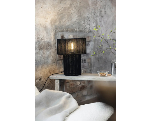 Dekorativ bordslampa med svart lampskärm på ett sidobord