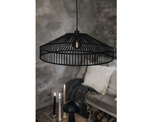 Svart hänglampa med metallram ovanför ett bord med ljus och dekoration.