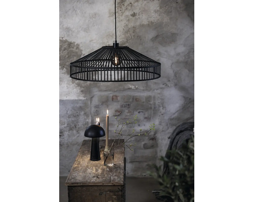 Svart hängande metallampa ovanför ett träbord med dekoration