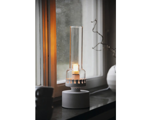 Dekorativ bordslampa med glasskärm och varmt sken på en fönsterbräda.