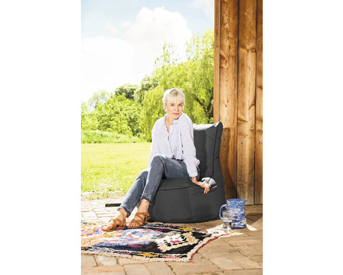 Kvinna sitter på en grå sittsäck i trädgården